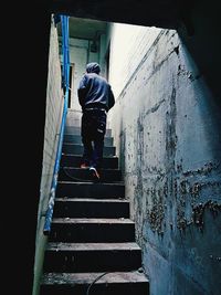 Rear view of man on staircase against wall