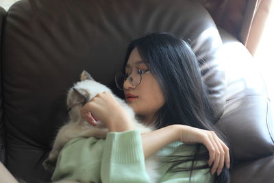 High angle view of young woman with cat lying on sofa at home