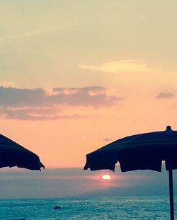 Silhouette beach umbrella against sky during sunset