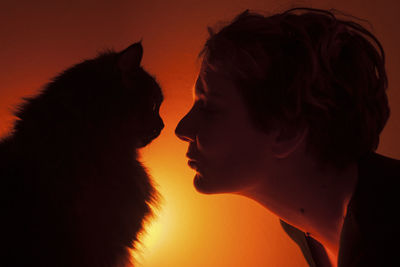 Close-up portrait of silhouette woman against orange sky