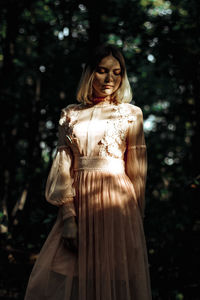 Woman standing by tree against plants