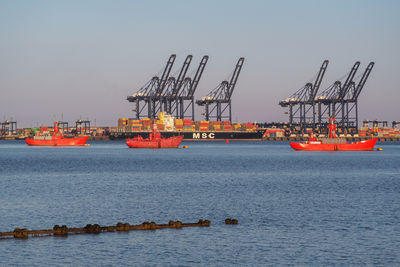 Cranes at commercial dock against clear sky