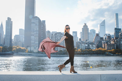 Full length of woman with arms outstretched against river