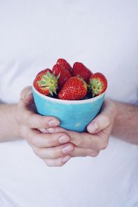 Midsection of man holding strawberries in bowl