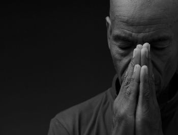 Close-up of man with hands against black background