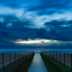 Footpath leading towards bridge against sky