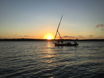 Silhouette sailboat in sea against sky during sunset