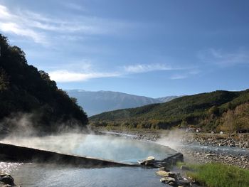 Scenic view of thermal pool amidst mountains against sky