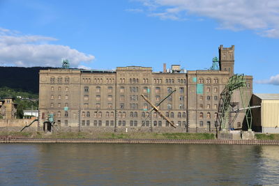 Building by river against sky in city