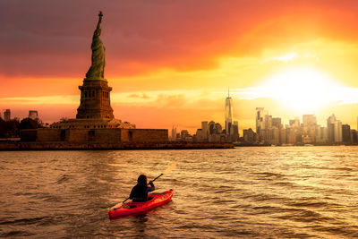 Man on boat in city during sunset