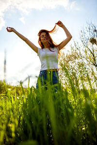Full length of young woman standing on grassy field