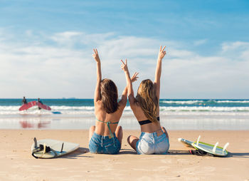 Friends enjoying at beach against sky