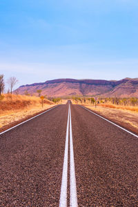 Road leading towards mountains against sky