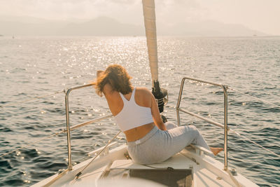 Female relaxing on bow of sailboat in the sun on vacation while sailing in the mediterranean.