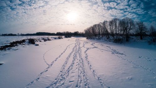 Snow covered field against sky during winter
