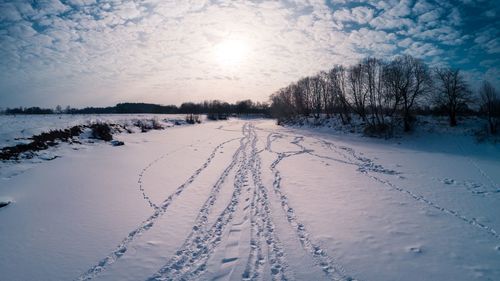Snow covered field against sky during winter