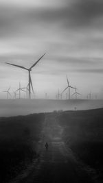 Wind turbines on field against sky