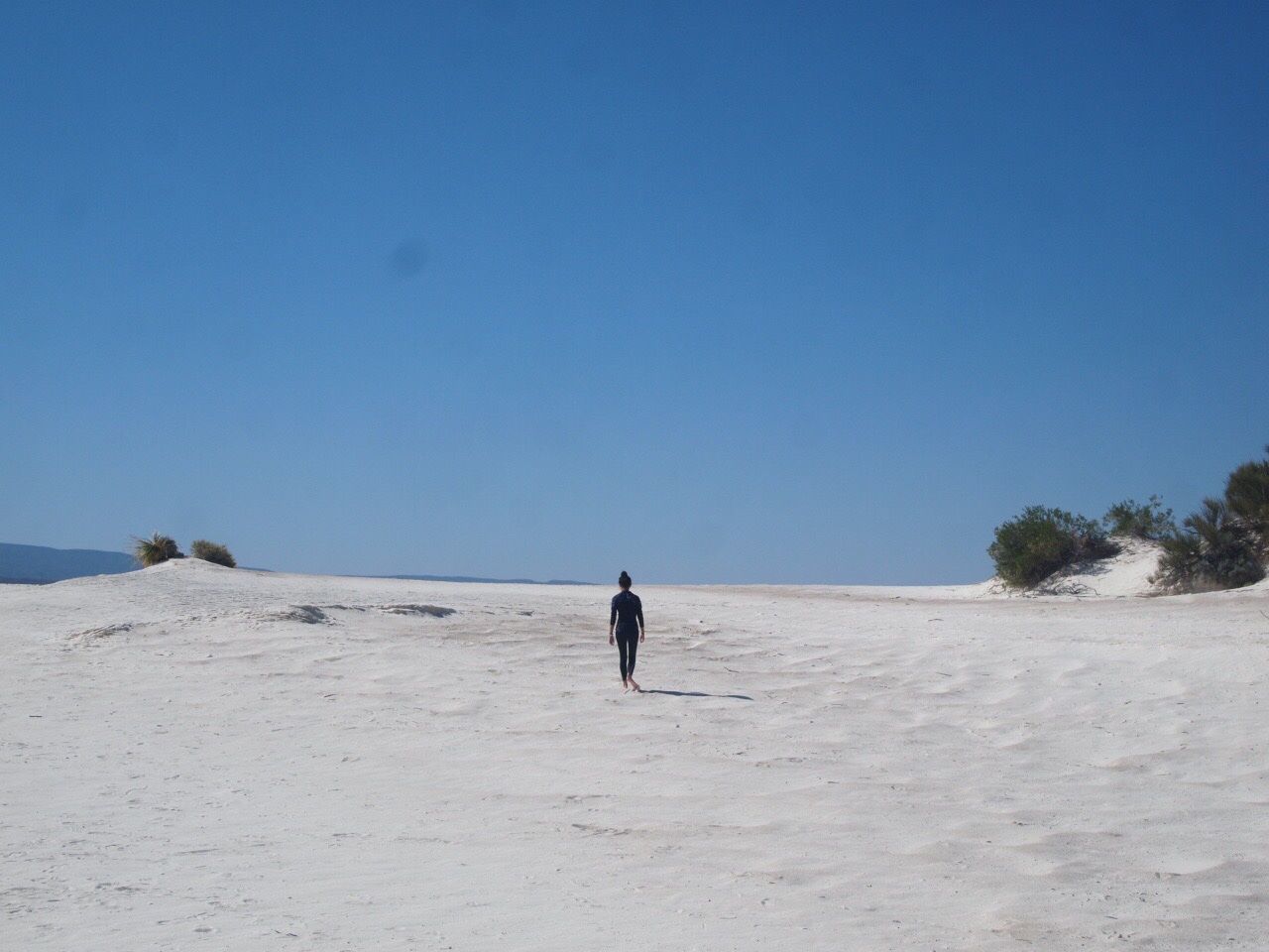 REAR VIEW OF MAN WALKING ON SAND AT BEACH