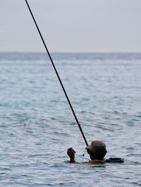 Fishing rod on sea against sky