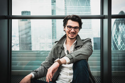 Smiling man sitting against window