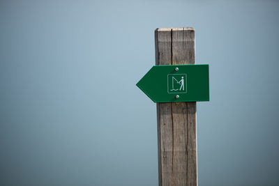 Close-up of sign on wooden post against clear sky