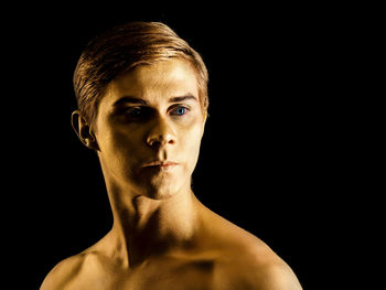 Close-up of male ballet dancer against black background