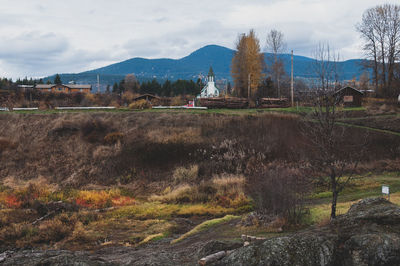 Scenic view of field by buildings against sky