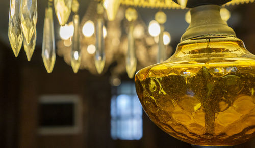 Close-up of illuminated lighting equipment hanging in glass