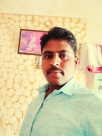 Portrait of young man standing against wall at home