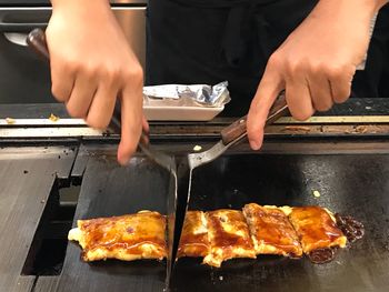 Close-up of man preparing food on barbecue grill