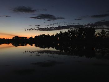 Silhouette trees by lake against sky during sunset