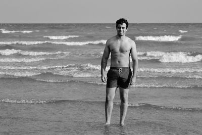 Full length of shirtless man standing at beach
