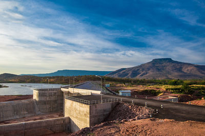 Scenic view of dam and mountains against sky