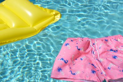 Close-up of raft and shorts floating on swimming pool