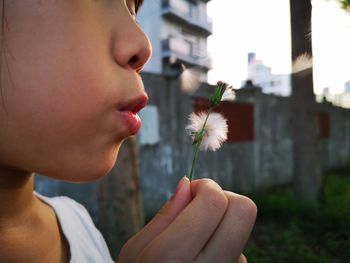 Close-up portrait of beautiful woman holding dandelion