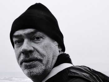 Close-up portrait of man wearing knit hat against clear sky