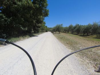 Road amidst trees against clear blue sky