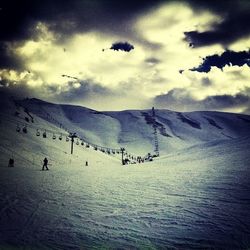 Scenic view of snow covered mountains against cloudy sky