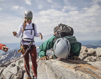 Male climber kisses summit marker of grand teton while friend watches