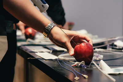 Close-up of man injecting apple on table