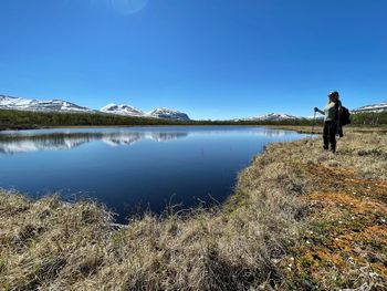 Women standing by lake against sky