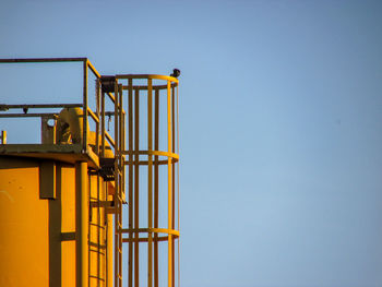 Low angle view of yellow metal against clear sky