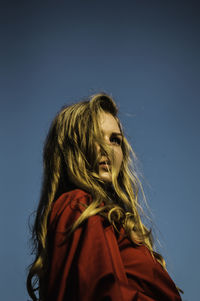 Low angle view of young woman looking away against sky