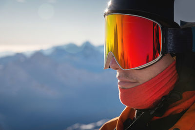 Close-up portrait of a guy holding skis in winter, he is wearing sportswear such as a helmet and