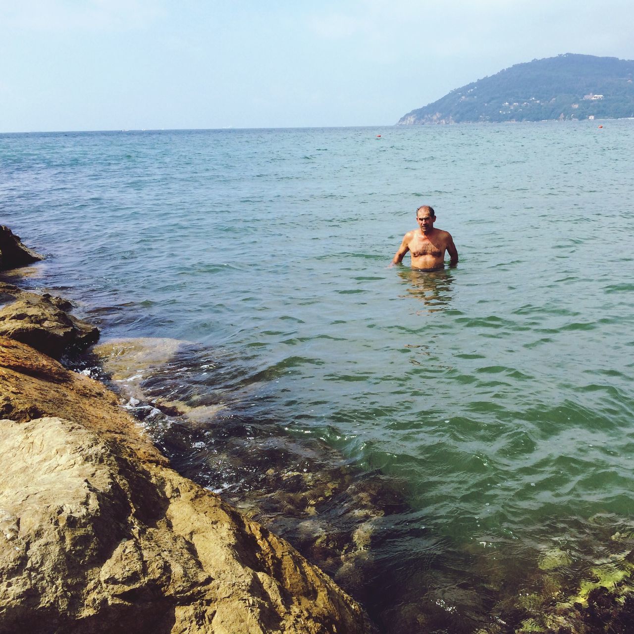 water, sea, leisure activity, lifestyles, scenics, beauty in nature, men, tranquil scene, mountain, tranquility, nature, full length, clear sky, rear view, rock - object, idyllic, vacations, standing