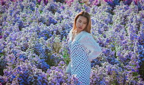 Woman standing by purple flowering plants