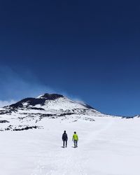 People walking on snowcapped mountain against sky