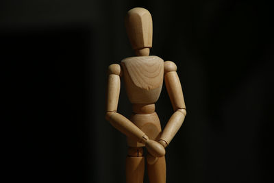 Close-up of figurine sculpture on wood against black background