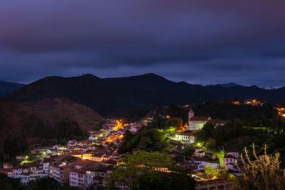 Illuminated buildings in town against sky at night