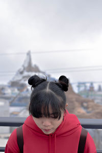 Young woman with pigtails wearing red hooded shirt in city